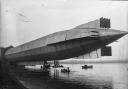 The HMA1 (Mayfly) emerges from its shed on Cavendish Dock in 1911 with sailors in rowing boats underneath.