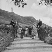Group of well-dressed children and one woman at Hoad entrance gates in the early 20th century