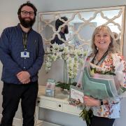 Jack Monopoli, recruitment coordinator at Westmorland Homecare's South Lakeland branch, presents flowers to Helen Manning in recognition of her actions