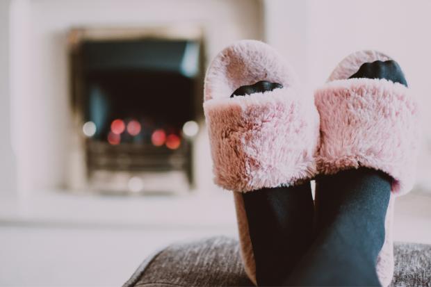 The Mail: A person putting their feet up in fluffy slippers in front of the fire. Credit: Canva