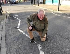 KNEEL: A local kneeling in a pothole, to show the size