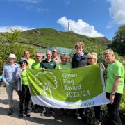 Staff and volunteers celebrate with the Green Flag award 2023/24 banner
