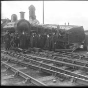 Workmen, dignitaries and a policeman pose alongside the crashed carriage. Derailed engine No 8's carriage wheels are to the right.