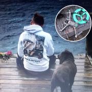 Jordan with his dog Alfie sitting next to some flowers left on a jetty at Coniston