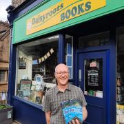 Paul Rand with copies of his novel outside Daisyroots Books in Grange
